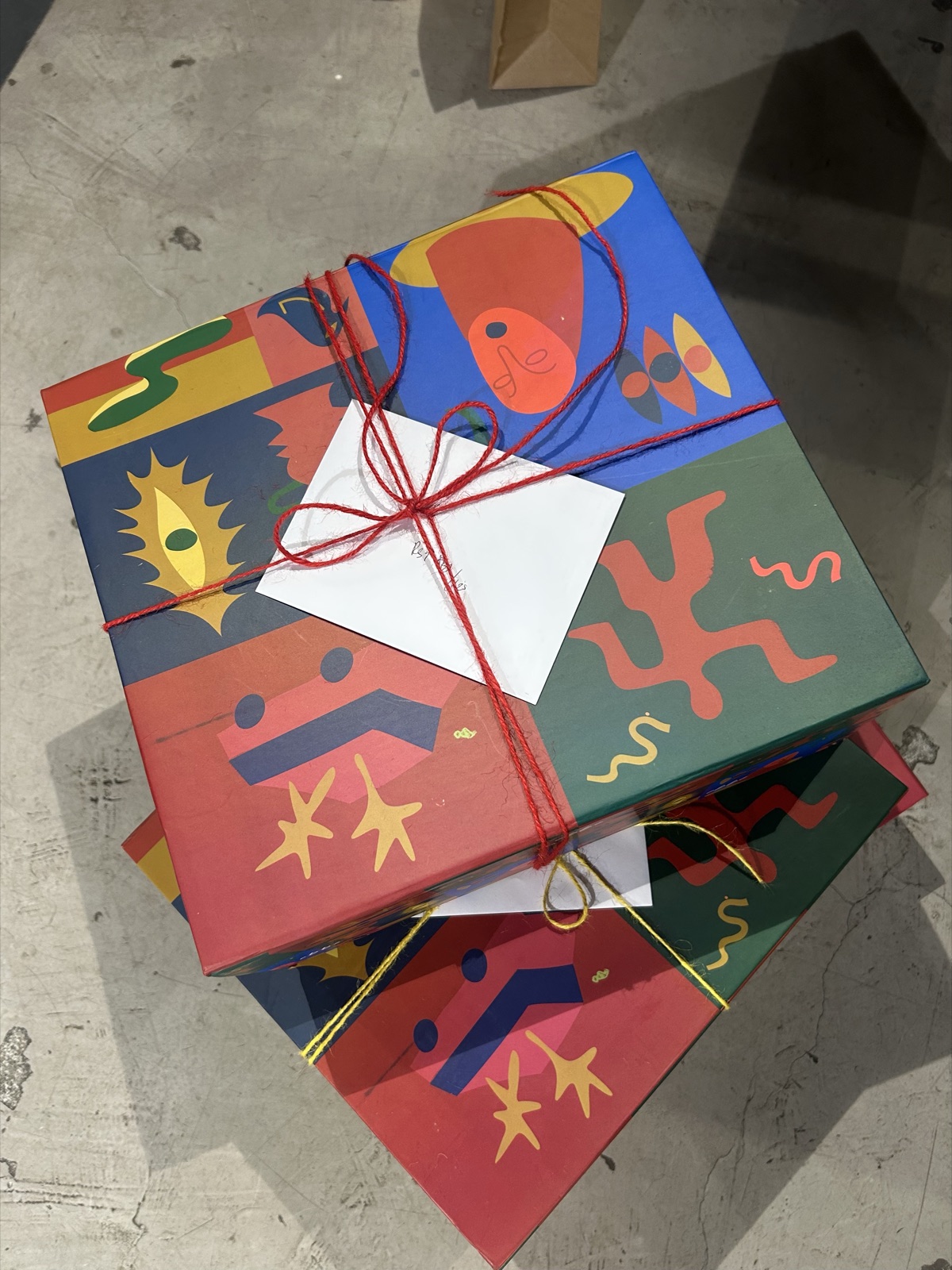 Stack of illustrated EBBE gift boxes tied with red string and a gift card